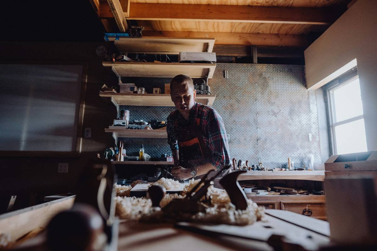 Infographic comparing garage-built vs. professional wooden workbenches showing key features like dog holes, vise placement, and wood hardness ratings