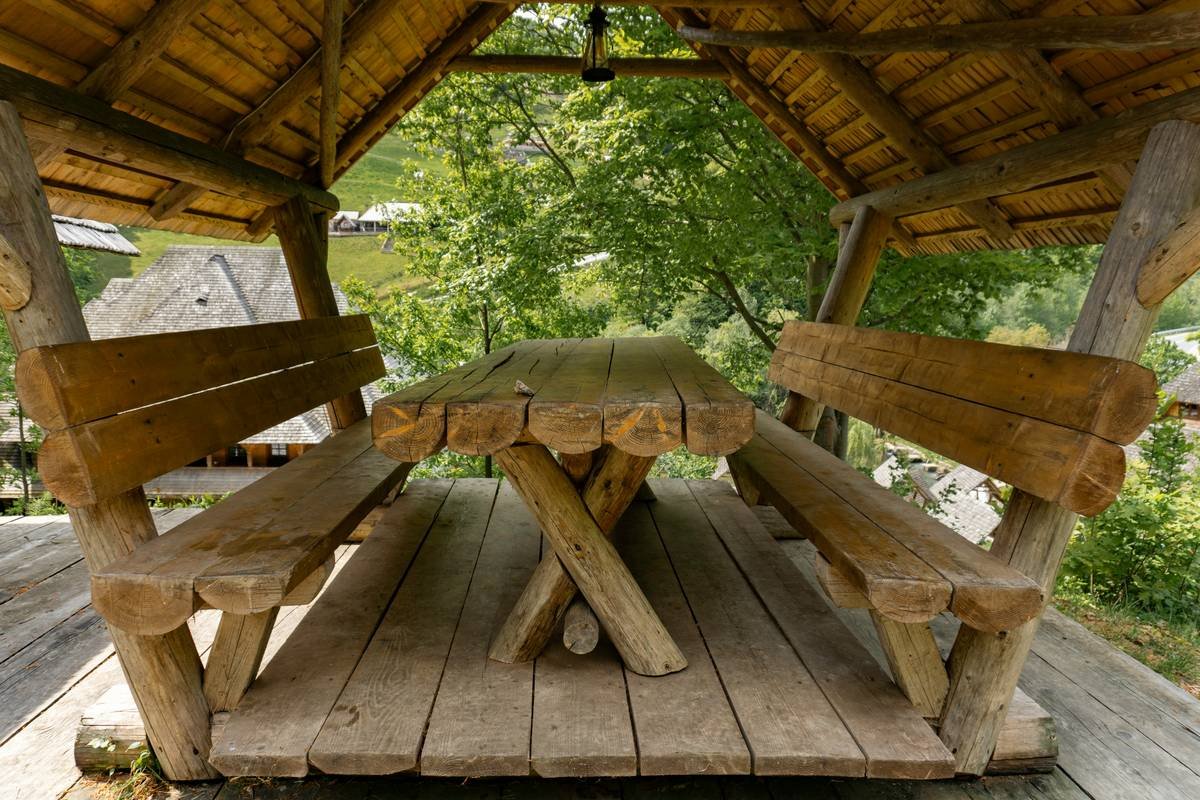 Comparison chart of outdoor bench and table materials showing durability ratings, maintenance needs, and ideal climates for teak, HDPE, metal, and stone